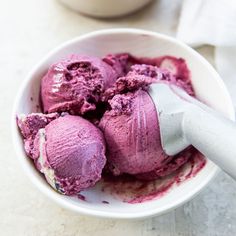 blueberry ice cream in a white bowl with a spoon next to it and the words, best milk blueberry ice cream