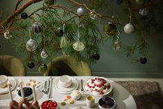 a table topped with plates and cups filled with desserts next to a christmas tree