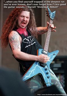 a man with long hair holding a blue guitar in front of an image of him