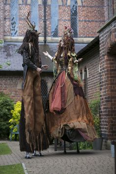 two people dressed in costume standing next to each other on a brick walkway near a building