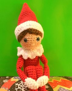 a crocheted christmas elf sitting on top of a cake