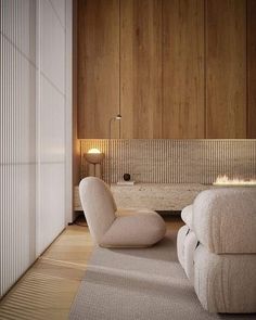 a living room with two white chairs and a rug on the floor in front of a wooden wall