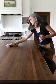 a woman standing at a kitchen counter with her hand on the edge of the table