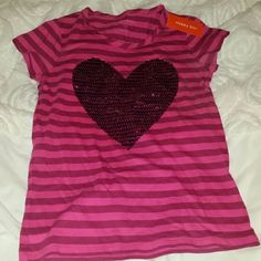 Girls Short Sleeve Shirt. Two-Tone Pink Stripe. Pink Sequin Heart On The Front. 100% Cotton. Cute Pink Heart Print Top, Cute Pink Top With Heart Print, Playful Short Sleeve Tops With Heart Print, Playful Cotton Tops With Heart Print, Playful Pink Tops With Heart Graphic, Playful Pink Top With Heart Graphic, Pink Cotton Heart Print Tops, Fun Cotton Tops With Heart Print, Pink Striped Shirt