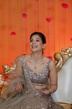 a woman sitting on top of a couch wearing a silver dress and smiling at the camera