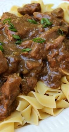 a white plate topped with pasta and beef sauce covered in gravy on top of it