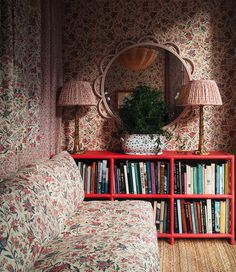 a living room with a couch, book shelf and mirror on the wall next to it