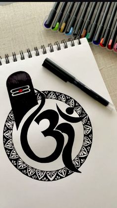 a drawing of an omen symbol in black on white paper next to colored markers