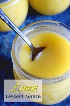 two jars filled with lemon dessert sauce and a spoon in one jar, on a blue surface