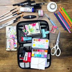 the contents of an art and craft kit are neatly organized on a wooden table,