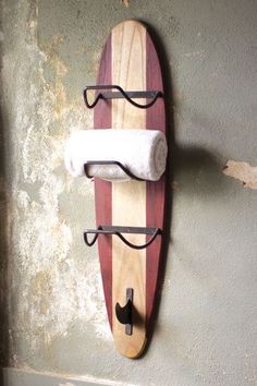 a surfboard mounted to the side of a wall with two towel racks on it