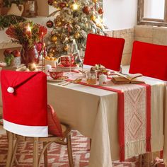 a dining room table with red chairs and a christmas tree in the background