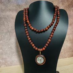 37" This Uniquely Designed Double Sided Photo Pendant Necklace Expertly Combines Wild Country Rosewood and Meditation Beads for an Elegant and Timeless Look. Handcrafted with Quality Materials, The ORIGINAL OSHO Rajneeshpuram Wild Country Rosewood Meditation Beads Mala Necklace Is the Perfect Accessory for Your Mindful Journey. ✥ Pendant size ✥ Necklace length - 37" (w/o pendant 35") ✥ Handmade by Artisans in India ❀❀❀Please look closely at photos as part of item description, the product in the Wooden Beads Amulet Necklace As A Gift, Amulet Style Wooden Beaded Necklace For Gifts, Amulet Style Wooden Beaded Necklace As Gift, Wooden Beads Amulet Necklace For Gift, Amulet Style Wooden Beaded Necklaces For Gifts, Brown Wooden Beads Holistic Necklace, Holistic Wooden Beads Necklace As A Gift, Holistic Style Necklace With Wooden Beads, Holistic Wooden Beads Necklace For Gift