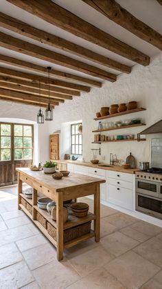 a kitchen with white walls and wooden beams on the ceiling is filled with natural materials