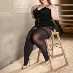 a woman sitting on top of a wooden chair wearing tights and stockings, posing for the camera