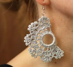 a close up of a person wearing some kind of earring that is made out of silver beads