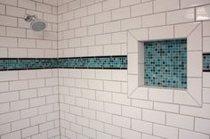 a white tiled shower with blue and green tiles