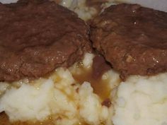 two hamburger patties covered in gravy and mashed potatoes