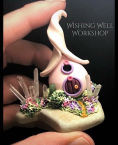 a hand is holding a small toy with a house on it's back and the words wishing well workshop above it