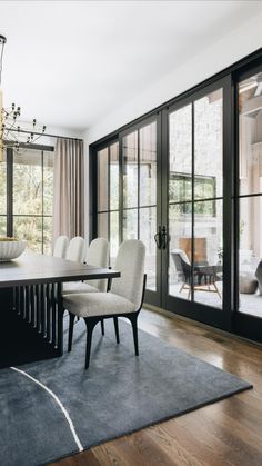 a dining room table with white chairs and a chandelier hanging from the ceiling