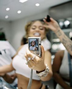 a woman taking a selfie with her cell phone in the foreground, while others look on