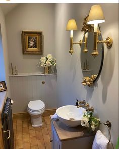 a white toilet sitting next to a sink in a bathroom under a mirror and two lights