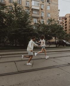 two people are running down the street with tennis rackets in their hands and one person is wearing white shoes