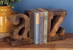 two books are placed next to each other on a wooden shelf with a potted plant in the background