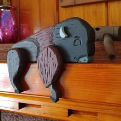 two wooden elephants are sitting on top of a shelf next to a purple glass vase