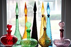 there are many different colored glass vases on the window sill