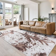 a living room filled with furniture and a large rug on top of a hard wood floor