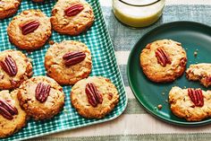 several cookies with pecans are on a green plate next to a glass of milk