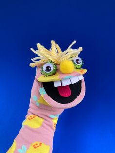 a hand with a knitted puppet on it's head and tongue sticking out