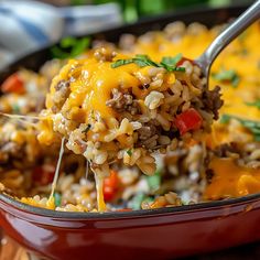 a spoon full of rice and ground beef being lifted from a casserole dish