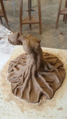 a clay sculpture of a woman sitting on top of a table next to some chairs