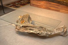 a glass and wood table sitting on top of a carpeted floor next to a rug