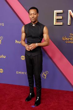 a man standing on top of a red carpet next to a purple and pink wall