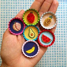 four miniature bottle caps with fruit and vegetables on them are held in someone's hand