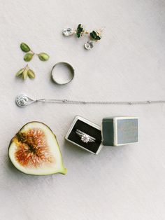 an apple, engagement ring and wedding band on a white surface with other jewelry items