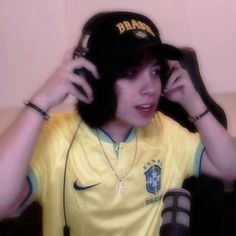 a young man wearing a yellow shirt and black hat with headphones in his ears