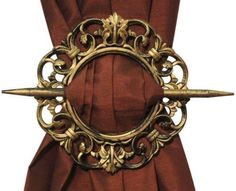 an ornate gold ring with two swords attached to the side of a red drapes