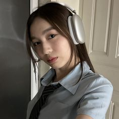 a young woman wearing headphones standing in front of a door