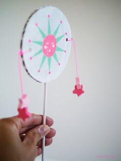 a hand holding a pink and white lollipop with stars on it's side