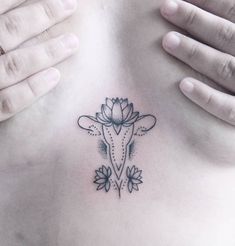 a woman's stomach with a flower tattoo on her chest and hands behind her