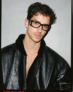 a man wearing glasses and a leather jacket