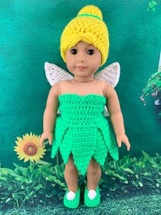 a crocheted doll is standing in front of a green wall with sunflowers