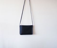 "This simple crossbody bag features black leather with fabric lining and a magnetic closure. Details: -Dimensions: 7\" length (top to bottom), 11\" top width and 9\" bottom width (side to side), 2\" depth, 9\" X 2\" base (bottom) -Shoulder strap is not adjustable. Please select the length. If you are not sure, please select \"other\" and email me your height. -Cotton interior lining (navy) - color can be customized -One internal slip pocket -Magnetic closure Because each bag is made by hand, the Minimalist Crossbody Shoulder Bag With Magnetic Closure, Black Clutch Flap Bag For Everyday Use, Black Flap Clutch Bag For Everyday Use, Versatile Black Flap Bag In Soft Leather, Everyday Black Clutch Flap Bag, Black Soft Leather Crossbody Flap Bag, Black Minimalist Evening Shoulder Bag, Black Crossbody Shoulder Bag With Magnetic Closure, Black Clutch Shoulder Bag With Magnetic Closure