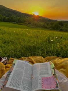 an open book sitting on top of a blanket next to a teddy bear in the grass