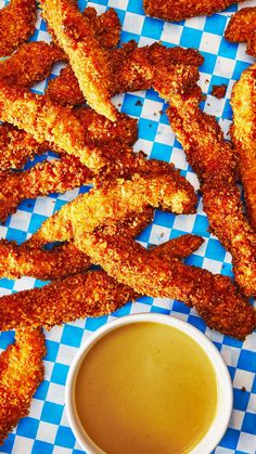 fried chicken sticks and dipping sauce on a blue checkered tablecloth with a cup