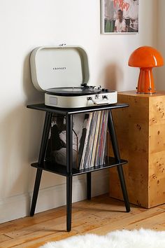 a record player sitting on top of a table next to an orange lamp and mushroom